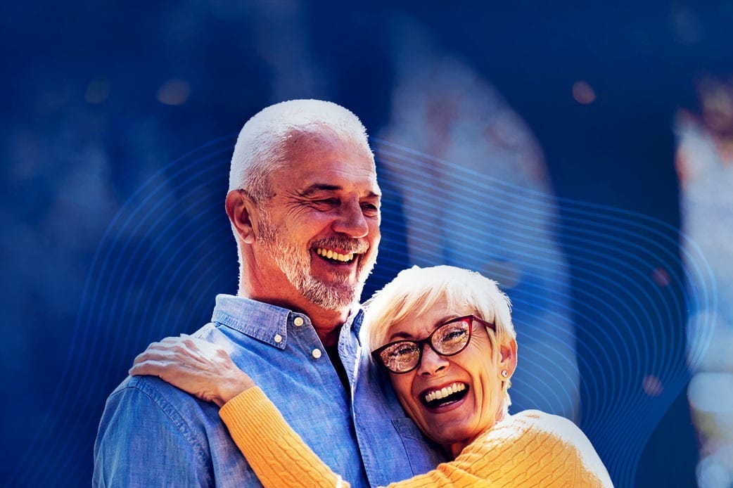 happy financially secure retired couple laughing and enjoying each other on a blue background.