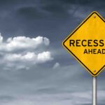 A yellow road sign that says "recession ahead" pictured with a stormy background.